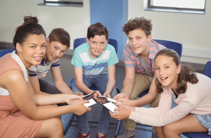 a group of kids sitting in a circle holding smartphones